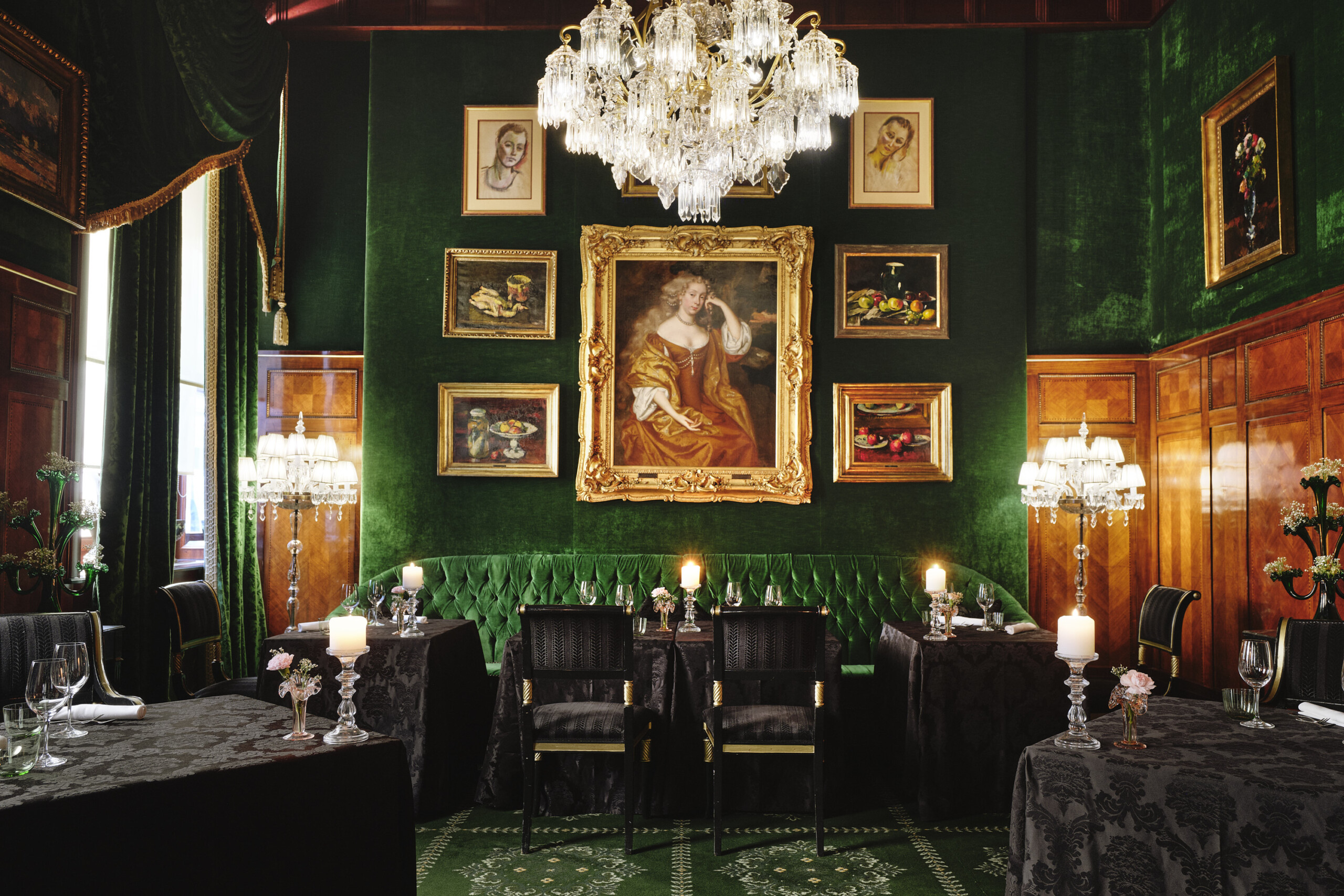 Opulent dining hall with set tables, white chairs, tall marble columns, and sparkling chandeliers