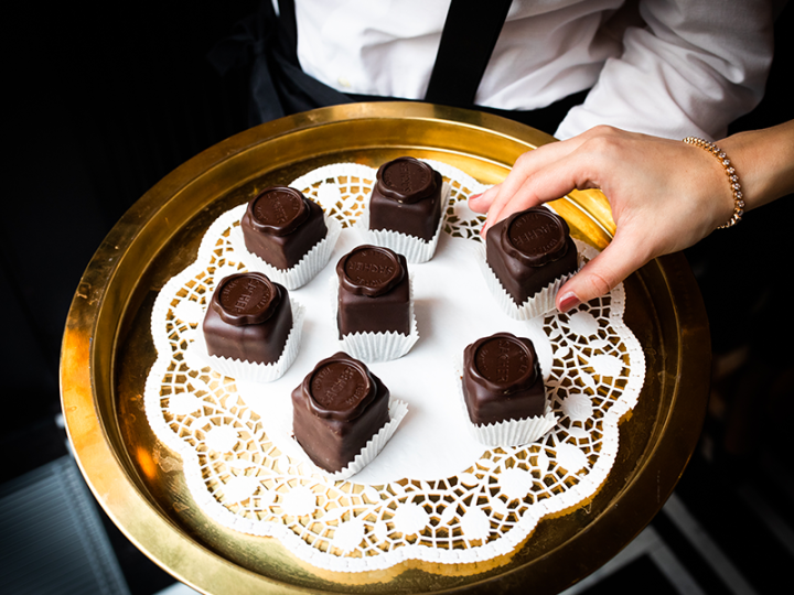 Golden serving platter with eight original Sacher cubes, lovingly arranged on lace doilies